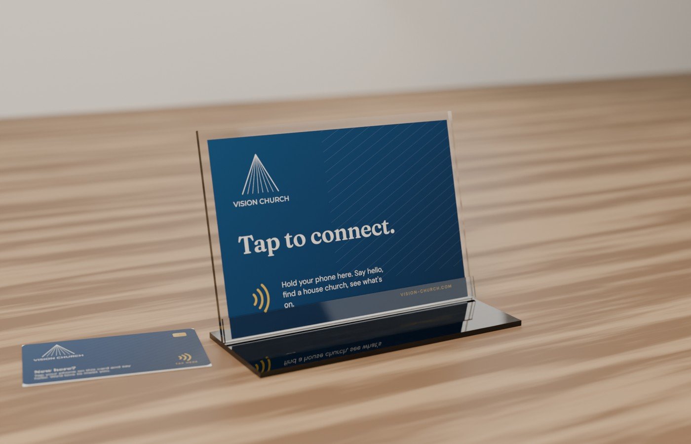 Vision Church's Tap Stand, an acrylic holder with a printed Tap to connect card, and a Tap Card beside it on a wooden table