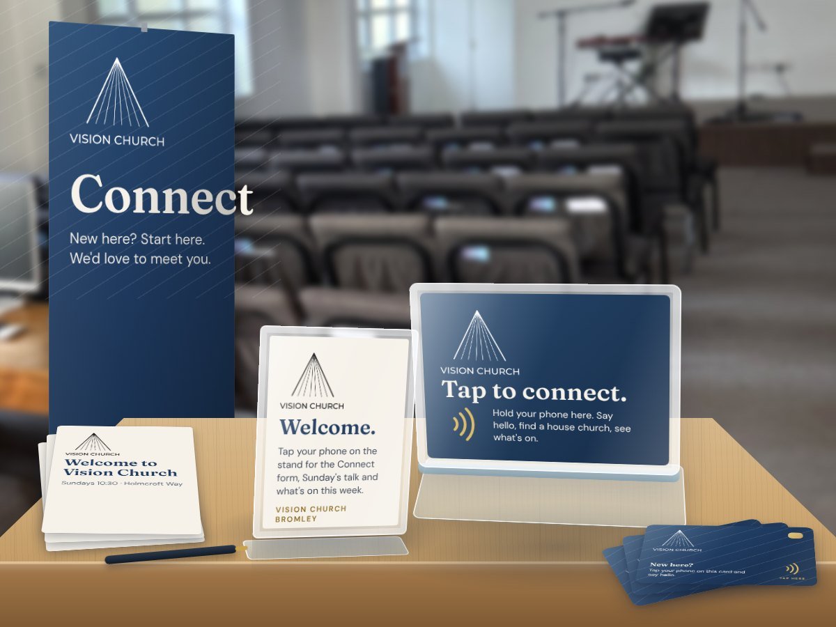 Vision Church's connect point: a pull-up banner, a Tap Stand, a welcome sign and Tap Cards on a table in the hall
